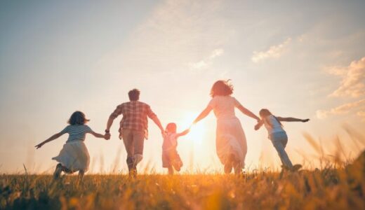 夕陽に向かって手をつないで走る５人家族