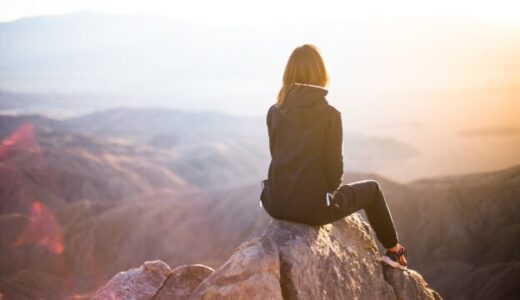 山の頂上で座っている後ろ姿の女性