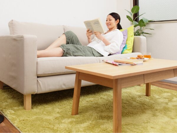 自宅のソファーで本を読んでゆったり過ごす女性