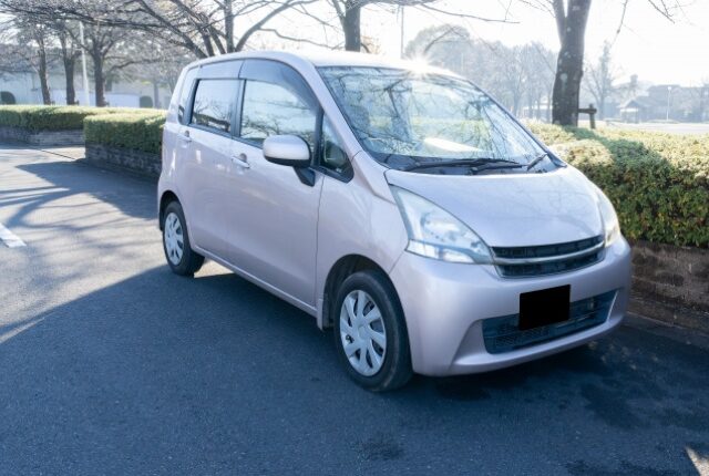 屋外に駐車してある薄いシルバーの軽自動車