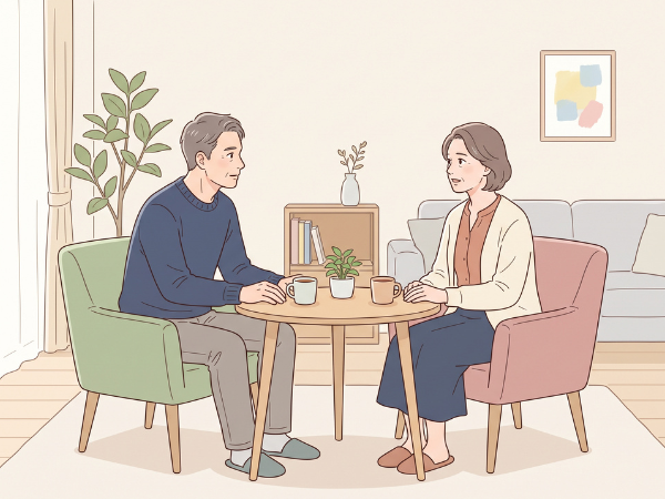 部屋で丸テーブル越しに椅子に座ってお互いのいろんな話をする50代男女