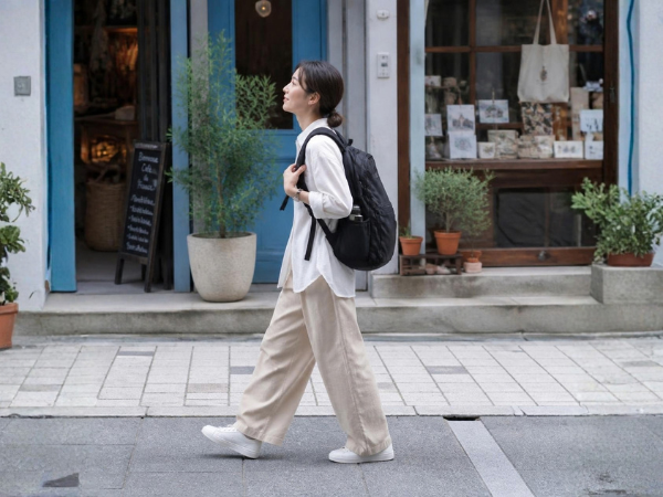 黒いリュックを背負って街中を歩く女性