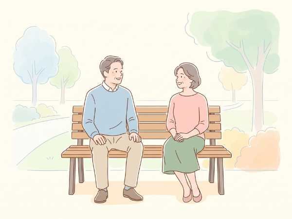 公園のベンチで程よい距離を取って笑顔で話す50代カップル